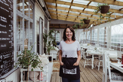 Portrait of senior businesswoman with hands in pockets standing in restaurant