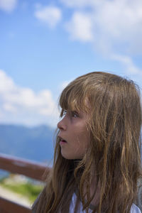 Close-up of girl looking away against sky
