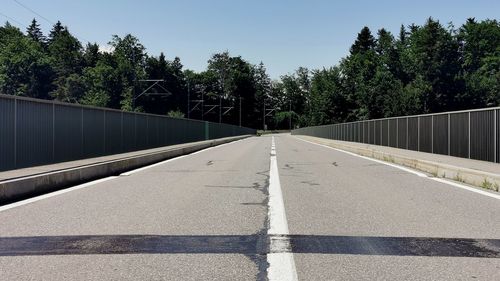 Road amidst trees against clear sky