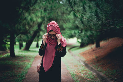 Full length of woman standing by plants in forest