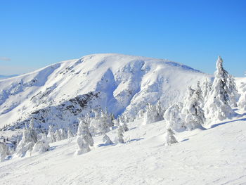 Scenic view of snowcapped mountains against clear blue sky