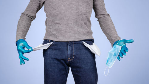 Midsection of woman holding umbrella against blue background