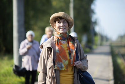 Portrait of smiling senior woman wearing summer hat traveling on during covid-19 pandemic