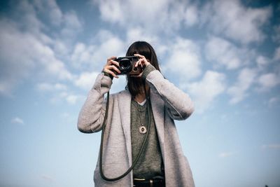 Woman photographing against sky