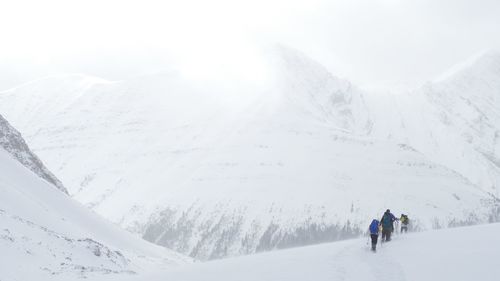 People on snow covered mountain against sky