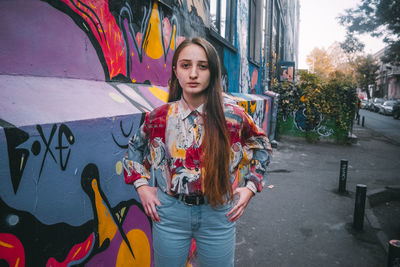 Portrait of young woman standing on street in city