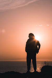 Rear view of silhouette man standing against sea during sunset