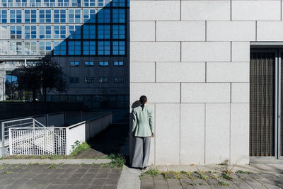 Businesswoman facing wall of office building