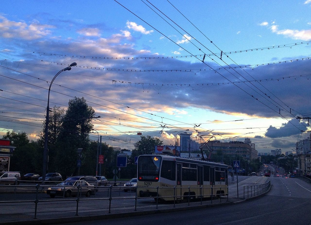 sky, electricity pylon, transportation, power line, cloud - sky, car, building exterior, electricity, mode of transport, road, street, cloudy, built structure, cable, cloud, land vehicle, power supply, sunset, architecture, dusk