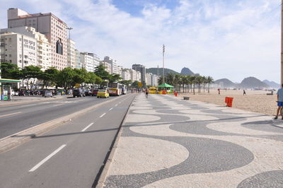 Road by buildings against sky in city