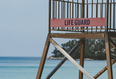 Information sign on beach against sky