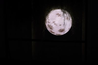 Close-up of moon against window at night