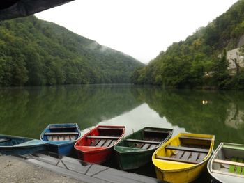 Boats moored on lake against sky