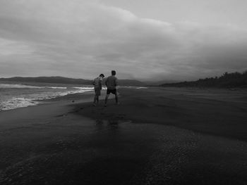 Rear view of men walking on beach