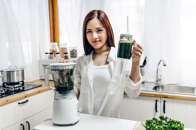 Portrait of young woman holding juice at home