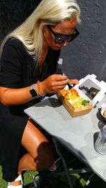 Midsection of woman holding ice cream while sitting on table