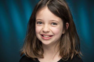 Portrait of smiling girl against blue backdrop