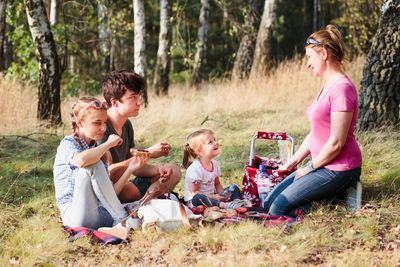 Mother with children having food on grassy field