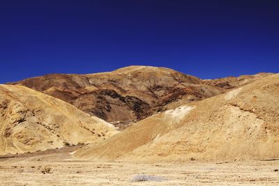 Scenic view of arid landscape against clear blue sky