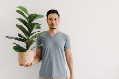 Portrait of young man standing against white background