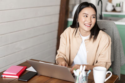 Portrait of young woman using laptop while sitting at home