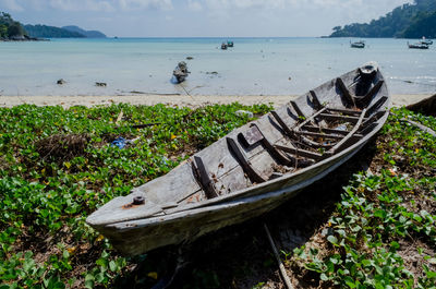 Abandoned boat moored on beach against sky