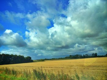 Scenic view of field against cloudy sky