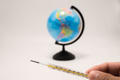 Cropped hand holding magnifying glass against white background