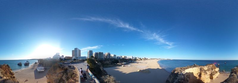 Panoramic view of sea and buildings against blue sky