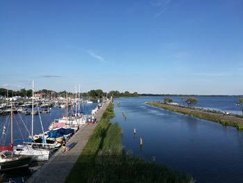 Boats moored at harbor against blue sky