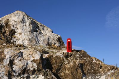 Red rock formation on mountain against clear blue sky