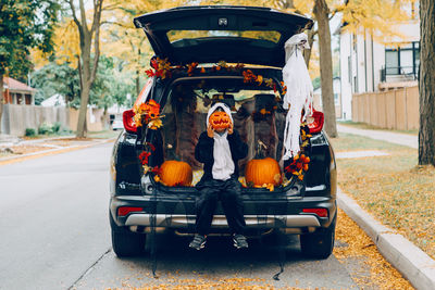 Cute kid sitting on car trunk in car