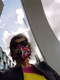 Portrait of woman wearing sunglasses and mask against sky