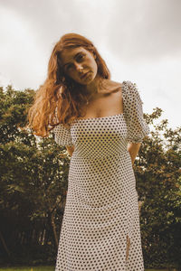 Portrait of young woman standing against tree