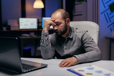 Young man using laptop at desk in office