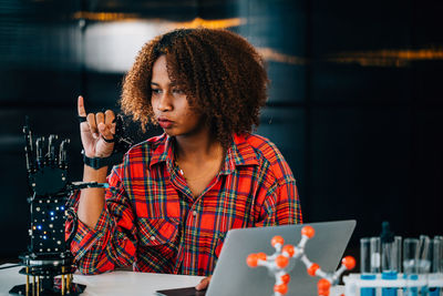 Young woman using mobile phone while sitting at cafe