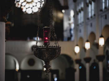 Close-up of illuminated lighting equipment hanging in a church