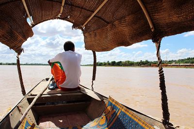 Rear view of man sitting in boat on river