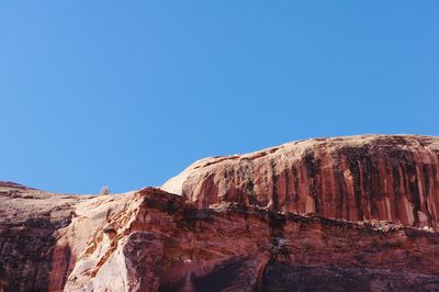 Low angle view of rock formations against clear blue sky