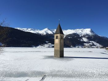 Built structure by snowcapped mountains against clear sky