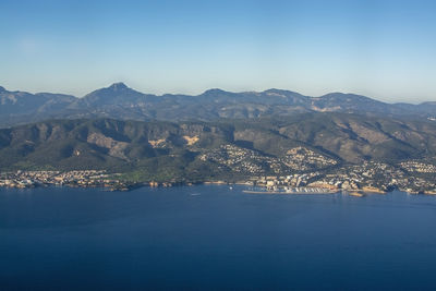 Aerial view of sea and mountains against clear blue sky