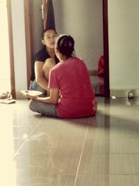 Young woman sitting on floor at home