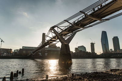 Bridge over river in city against sky