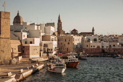 Boats in sea by buildings against sky in city