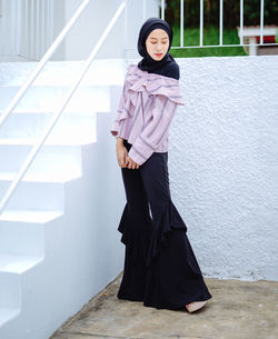 Portrait of woman standing against wall