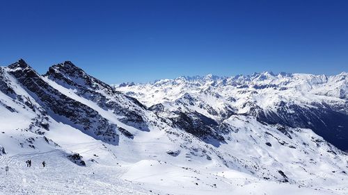 Scenic view of snowcapped mountains against clear blue sky