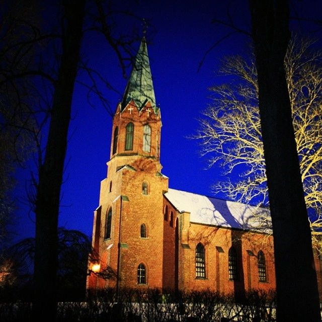 architecture, building exterior, built structure, bare tree, church, religion, place of worship, low angle view, tree, spirituality, branch, cathedral, clear sky, tower, sky, history, blue, steeple