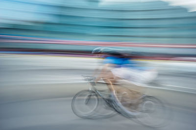 Blurred motion of man riding bicycle on street in city