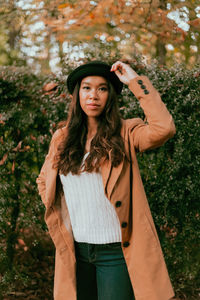 Portrait of thoughtful young woman standing in park during autumn