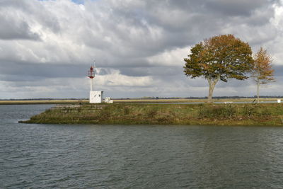 Lighthouse by sea against sky